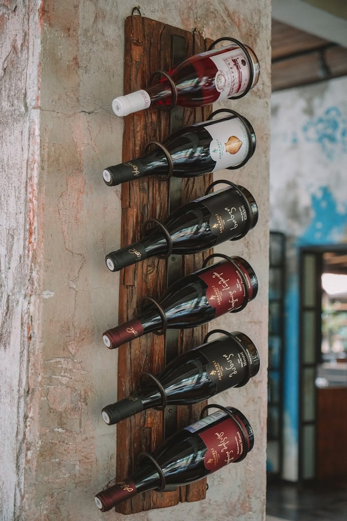 A rustic wooden rack elegantly displays various wine bottles against a textured wall.