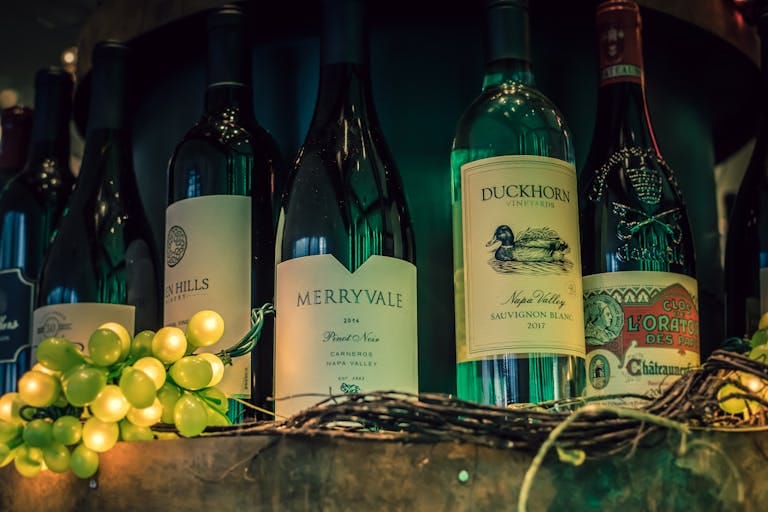 Close-up of wine bottles with green grapes, perfect for wine enthusiasts.