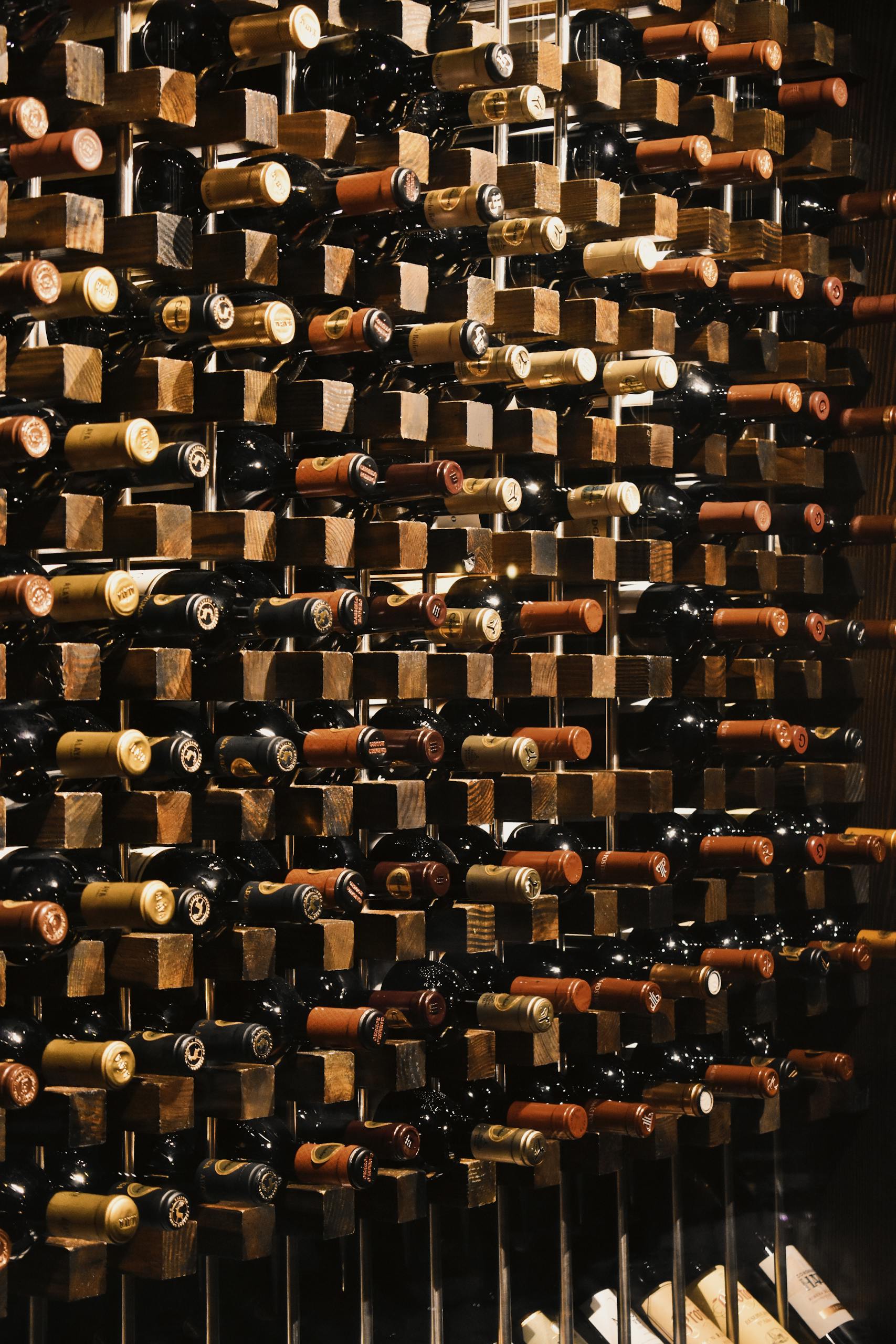 Vertical display of wine bottles on wooden racks, ideal for bars or cellars.