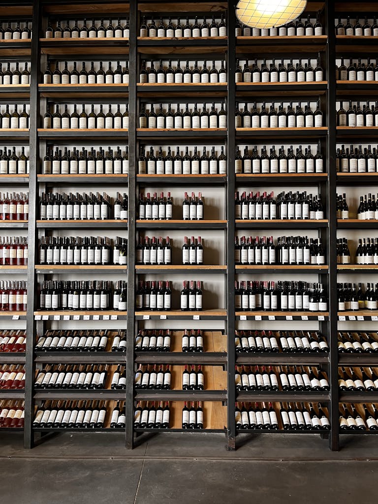 Vertical shot of wine bottles organized on shelves in a cellar.