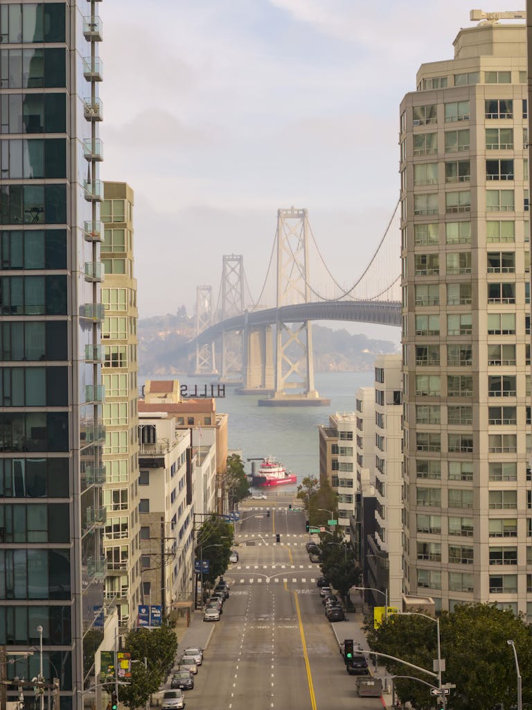 View of the Bay Bridge in San Francisco framed by urban architecture on a clear day.