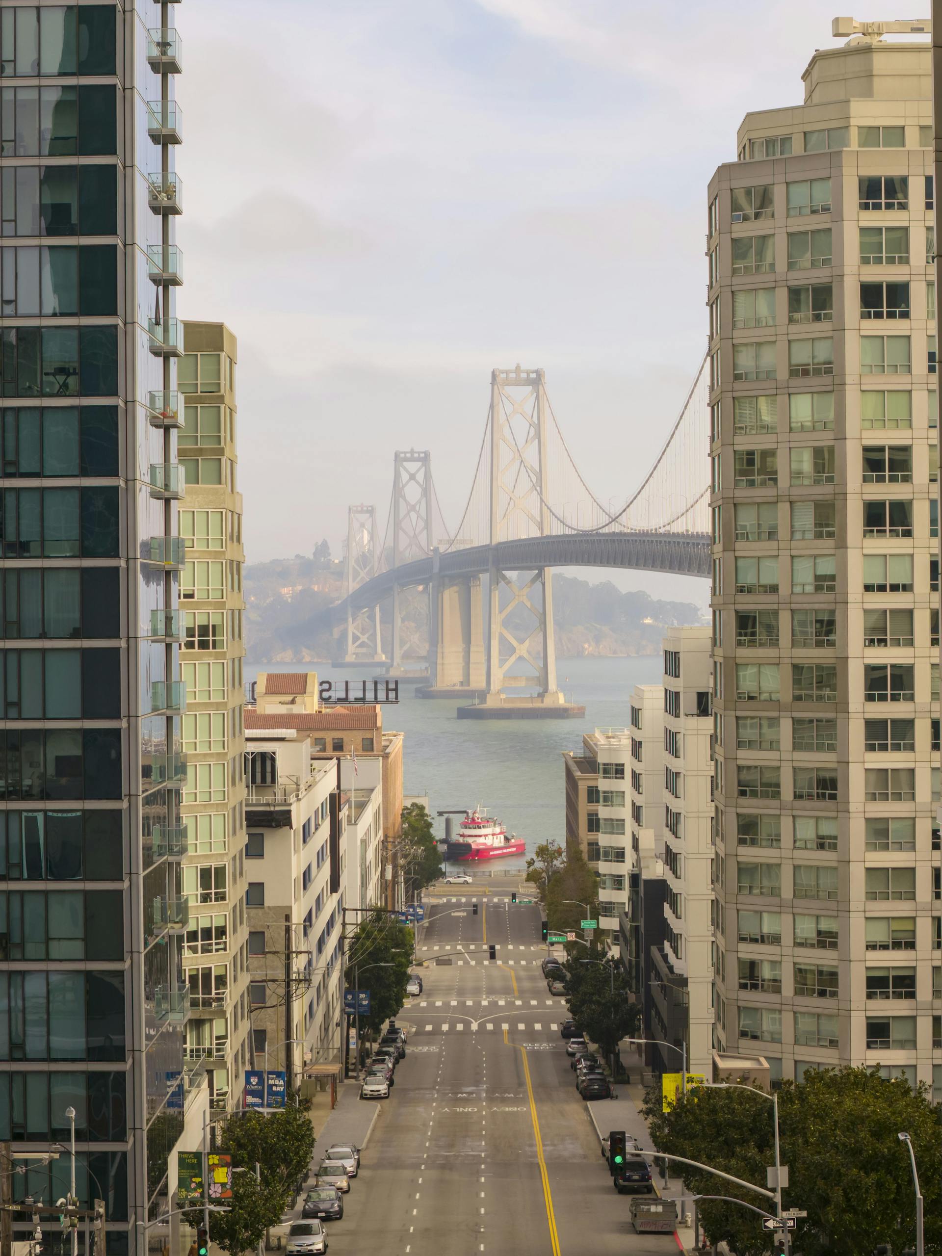 View of the Bay Bridge in San Francisco framed by urban architecture on a clear day.